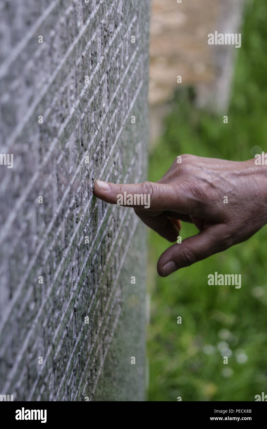 Woman's Hand berühren die Inschrift auf einem Grabstein Stockfoto