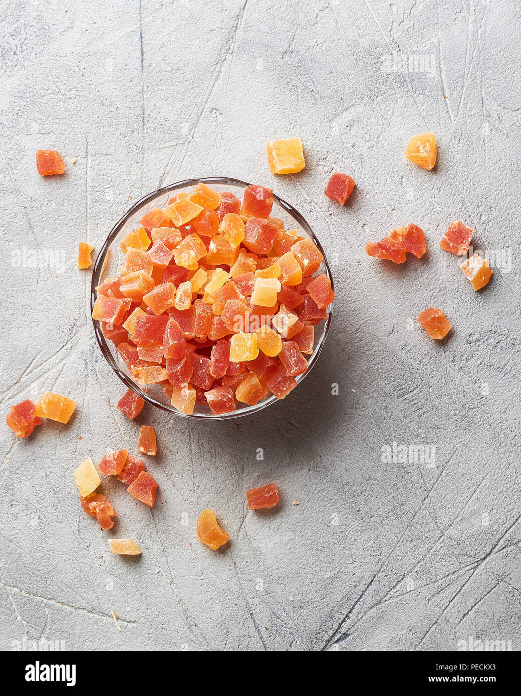 Würfel von getrockneten Aprikosen, Mangos und Papayas in der Schüssel. Kandierte Früchte über grauer Hintergrund mit kopieren. Ansicht von oben. Stockfoto