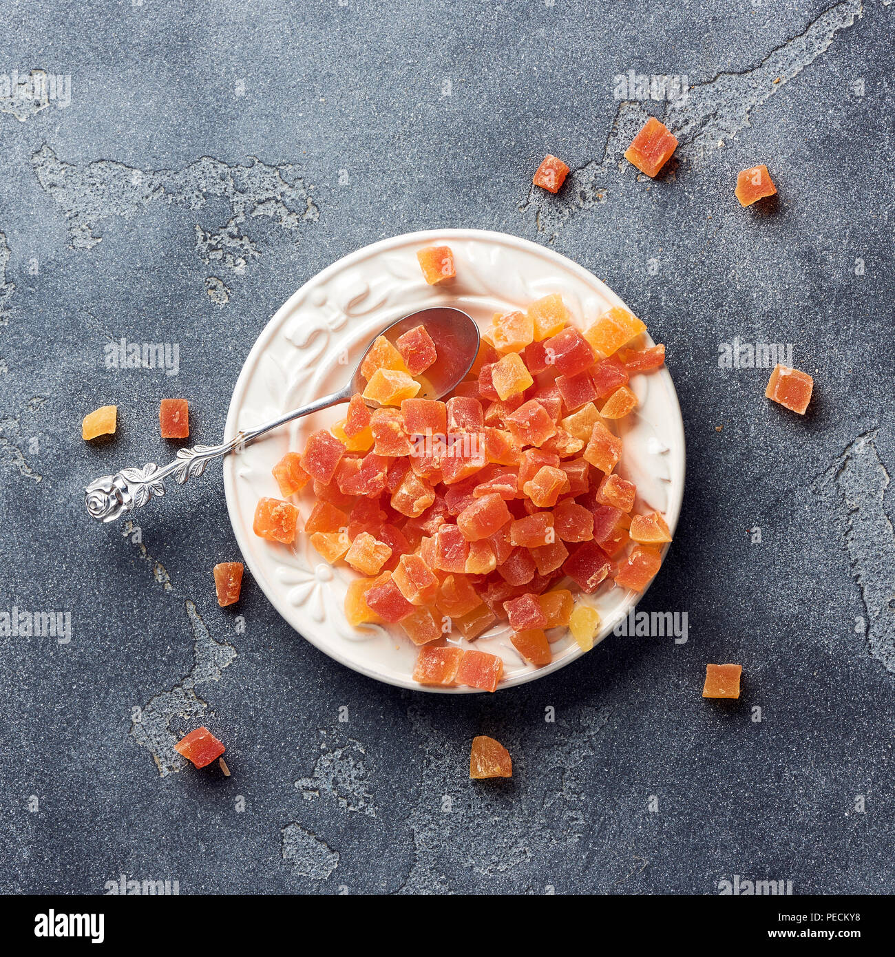 Würfel von getrockneten Aprikosen, Mangos und Papayas auf weiß palte. Kandierte Früchte über grauen Hintergrund. Stockfoto