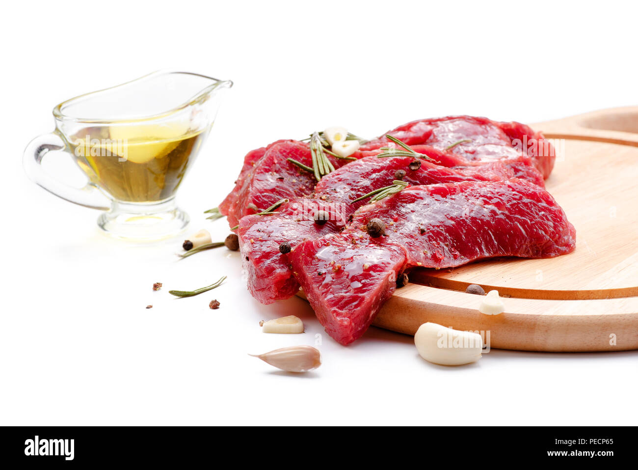 Stücke von Fleisch mit Knoblauch und Rosmarin auf weißem Hintergrund. Rohes Rindfleisch. Stockfoto