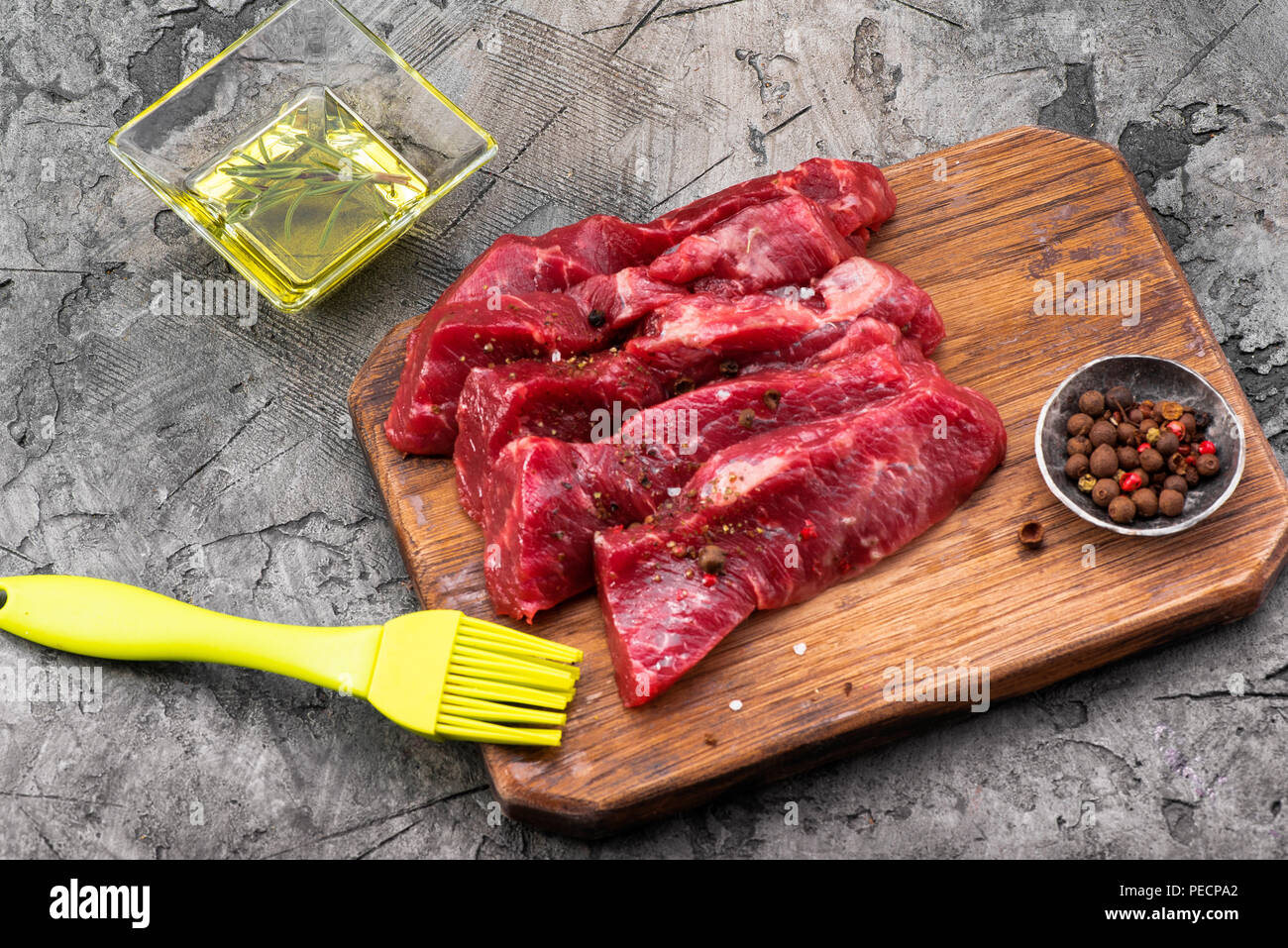Rohes Fleisch mit Olivenöl und Gewürzen auf Holzbrett. Frisches Rindfleisch. Bereit zum Rösten. Ansicht von oben. Stockfoto