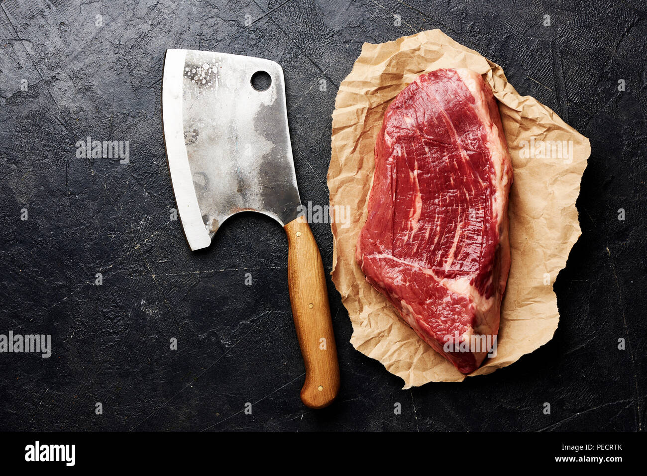 Rohe frische marmoriertes Fleisch Black Angus Steak auf braunem Papier und Fleisch Cleaver. Fleisch auf schwarzen Hintergrund mit kopieren. Ansicht von oben. Stockfoto