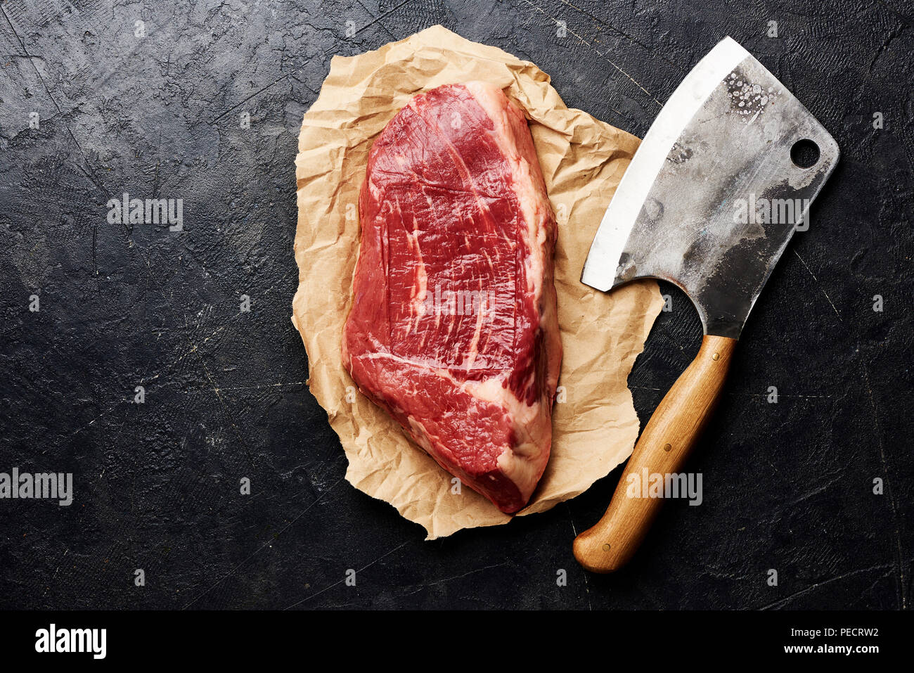 Rohe frische marmoriertes Fleisch Black Angus Steak und Fleisch Cleaver auf braunem Papier. Fleisch auf schwarzen Hintergrund mit kopieren. Ansicht von oben. Stockfoto