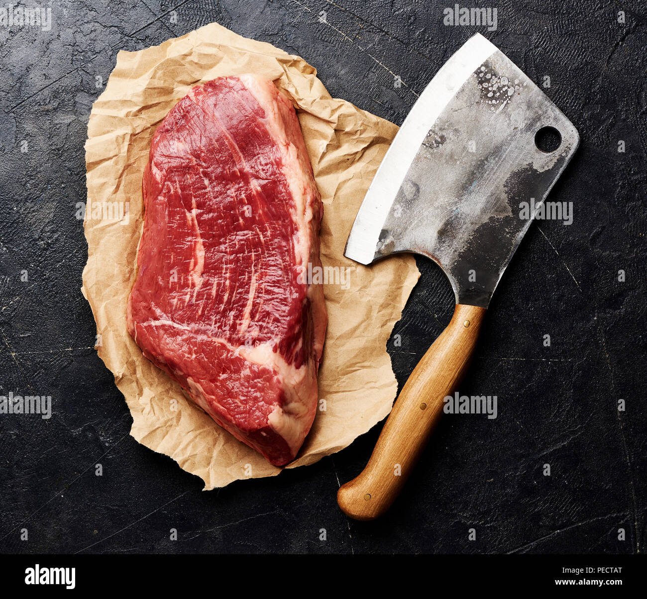 Rohe frische marmoriertes Fleisch Black Angus Steak und Fleisch Cleaver auf braunem Papier. Fleisch auf schwarzen Hintergrund mit kopieren. Ansicht von oben. Stockfoto