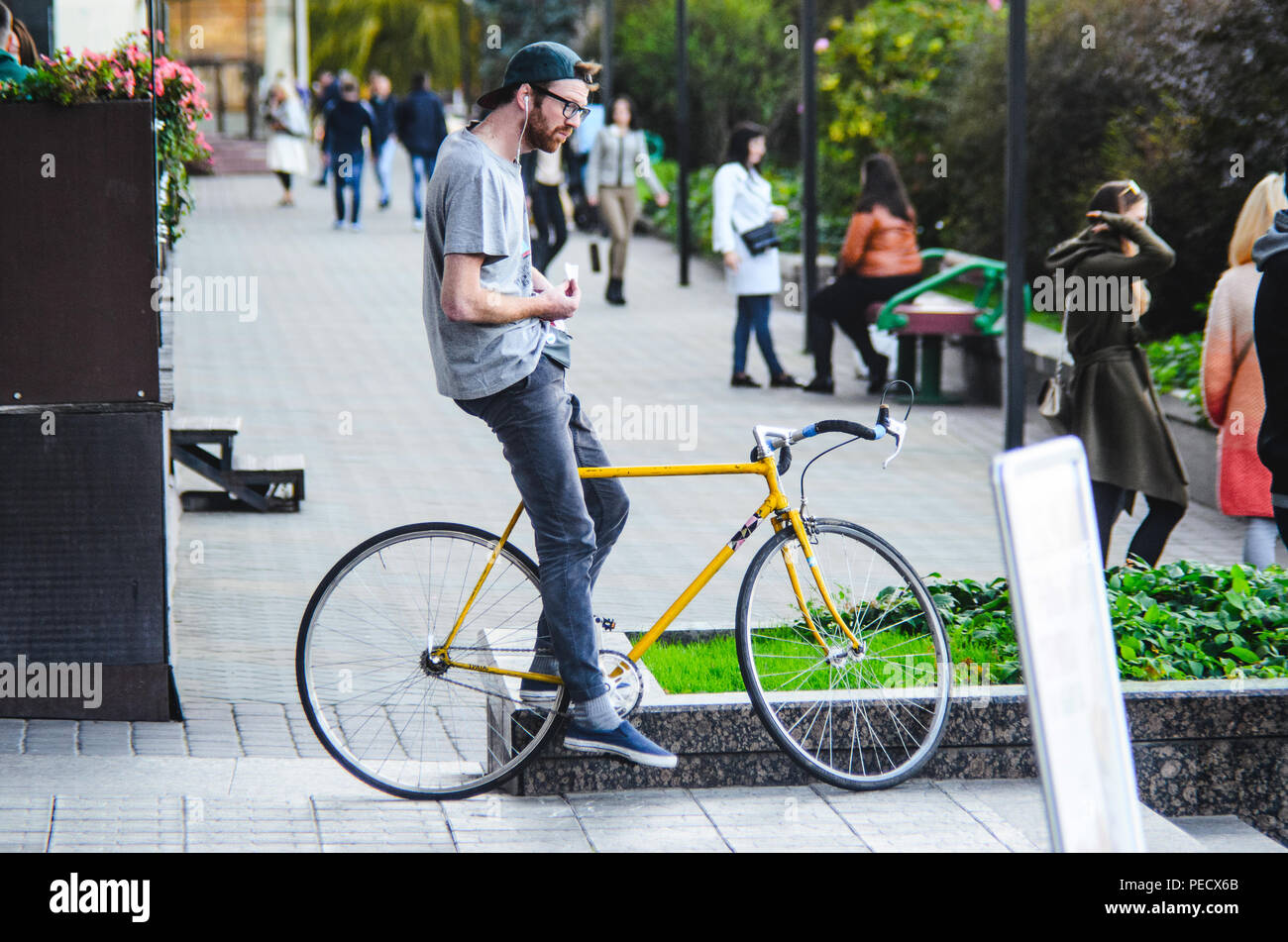 September 22, 2018 Minsk, Weißrussland: Junger Mann stand mit gelben fixie Bike im Stadtbild und macht Hand-roll Zigarette Stockfoto