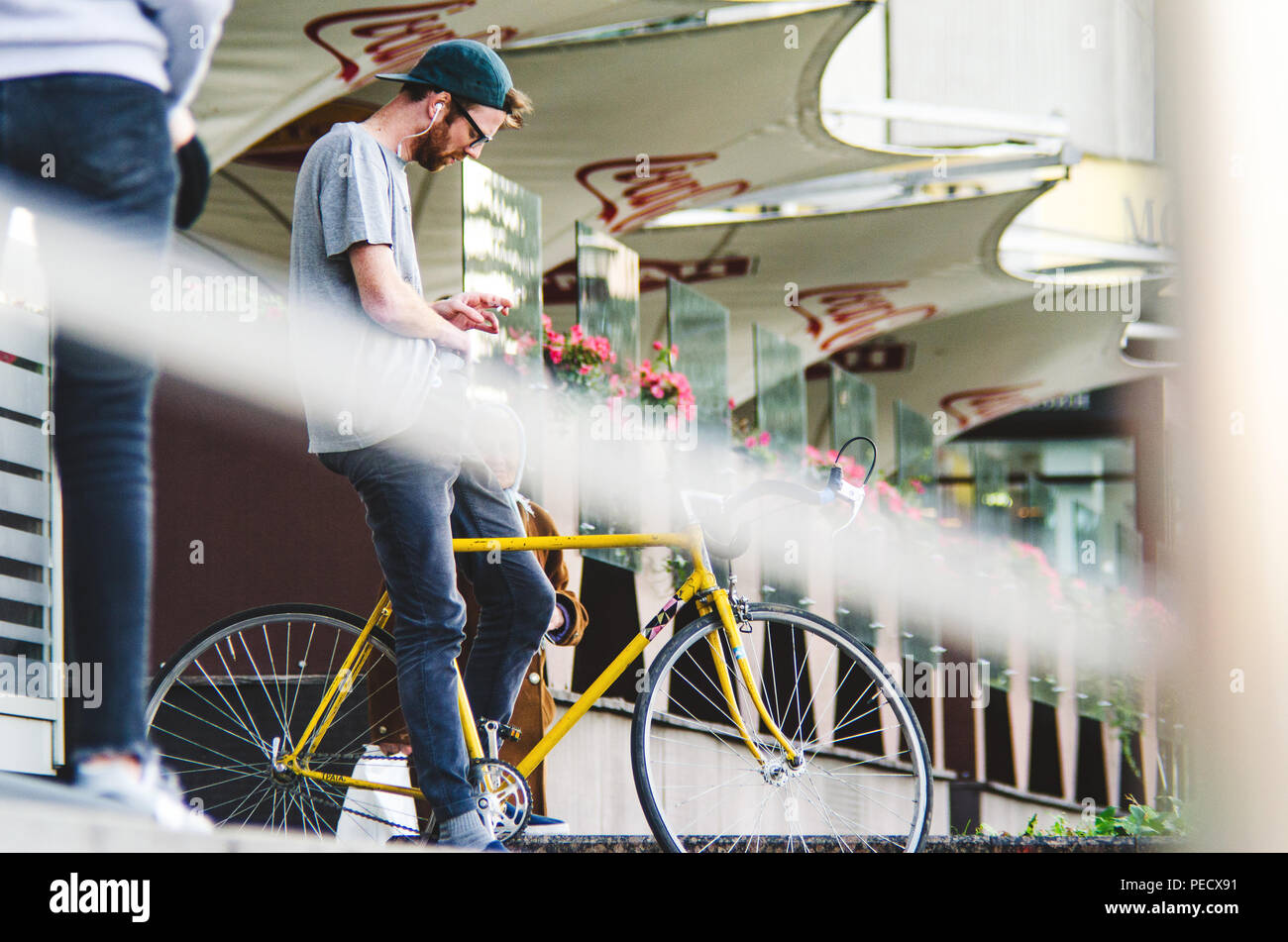 September 22, 2018 Minsk, Weißrussland: Junger Mann stand mit gelben fixie Bike im Stadtbild und macht Hand-roll Zigarette Stockfoto
