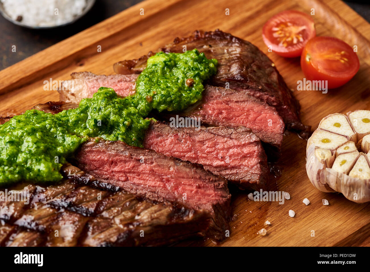 Black Angus Steak vom Grill mit Tomaten, Knoblauch mit chimichurri Sauce für Fleisch Schneidebrett. Stockfoto