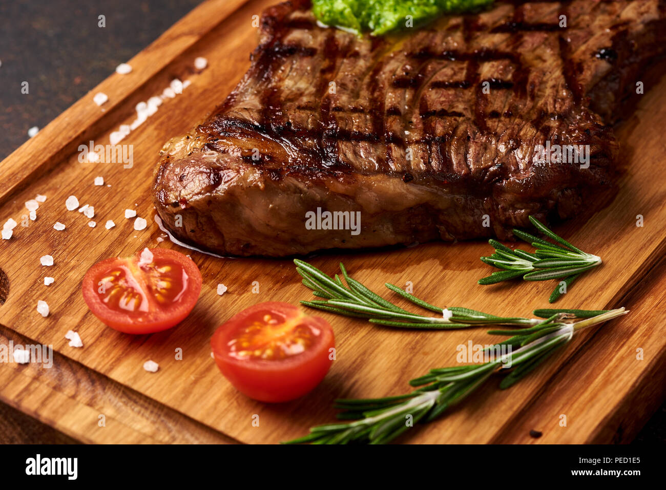 Black Angus Steak vom Grill mit Tomaten, Knoblauch mit chimichurri Sauce für Fleisch Schneidebrett. Stockfoto