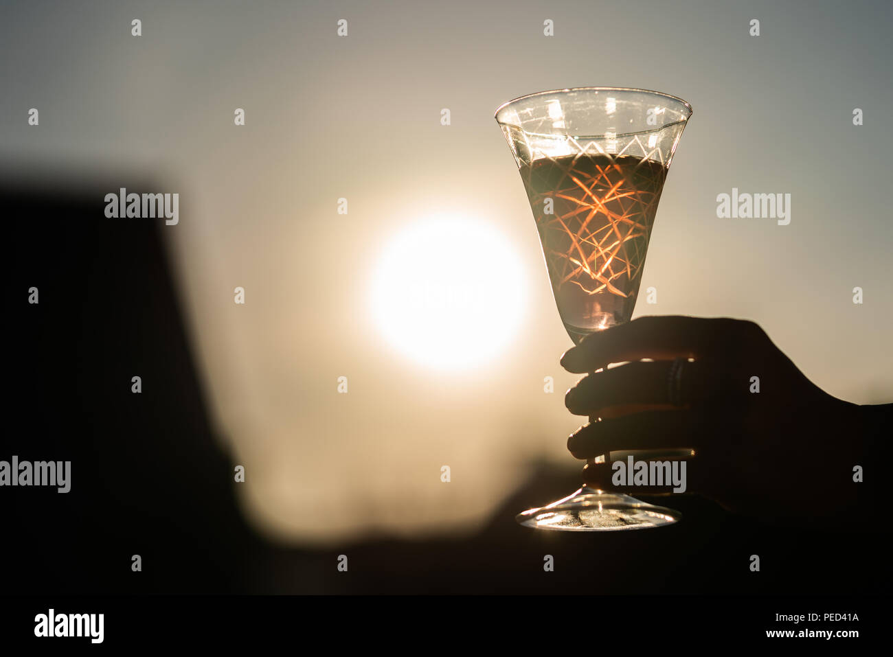 Ein Glas Wein wird von einer Frau direkt am Sunset statt. Stockfoto