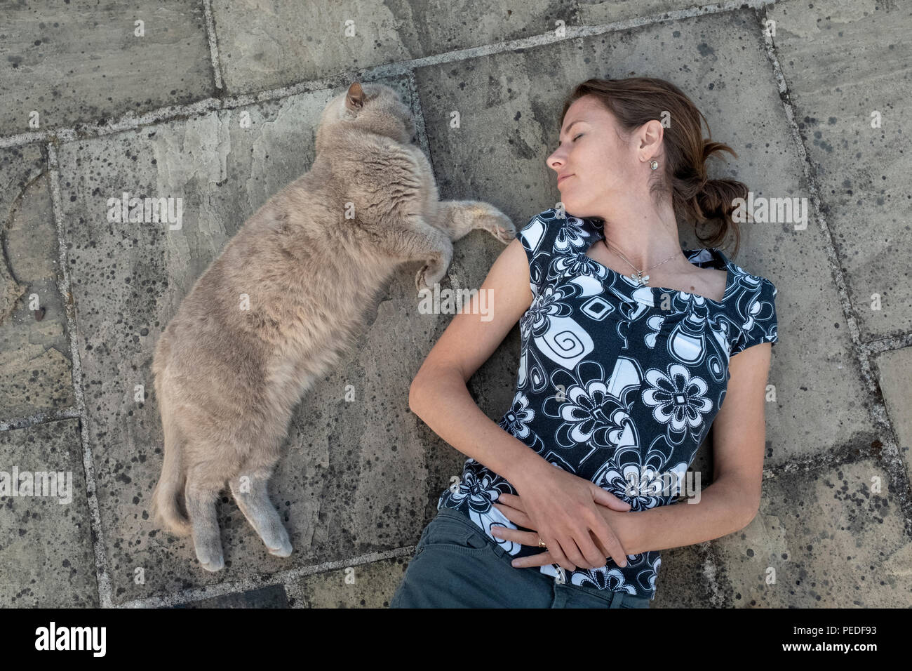 Eine Frau und ihre Katze zusammen auf dem Boden liegen. Stockfoto