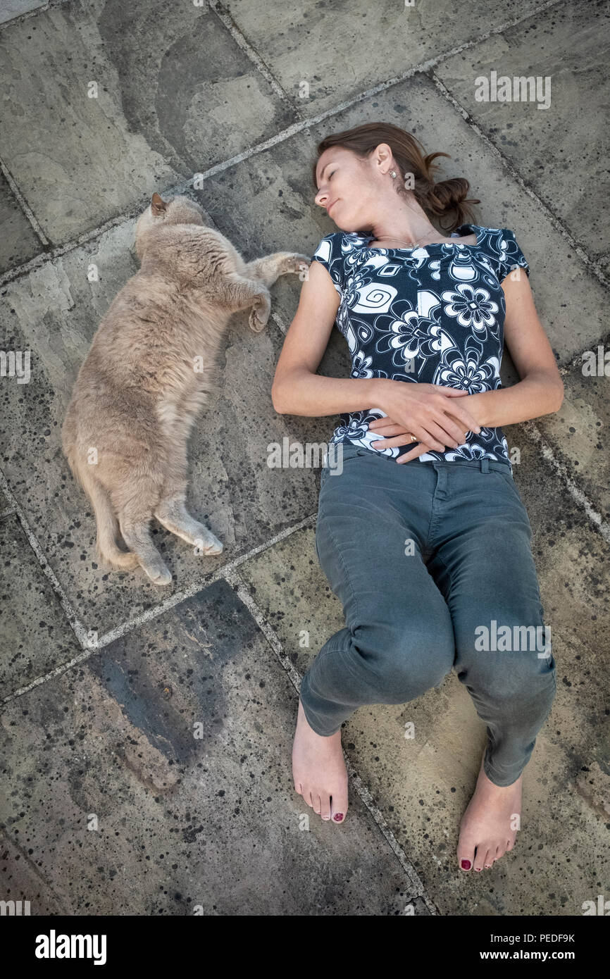 Eine Frau und ihre Katze zusammen auf dem Boden liegen. Stockfoto