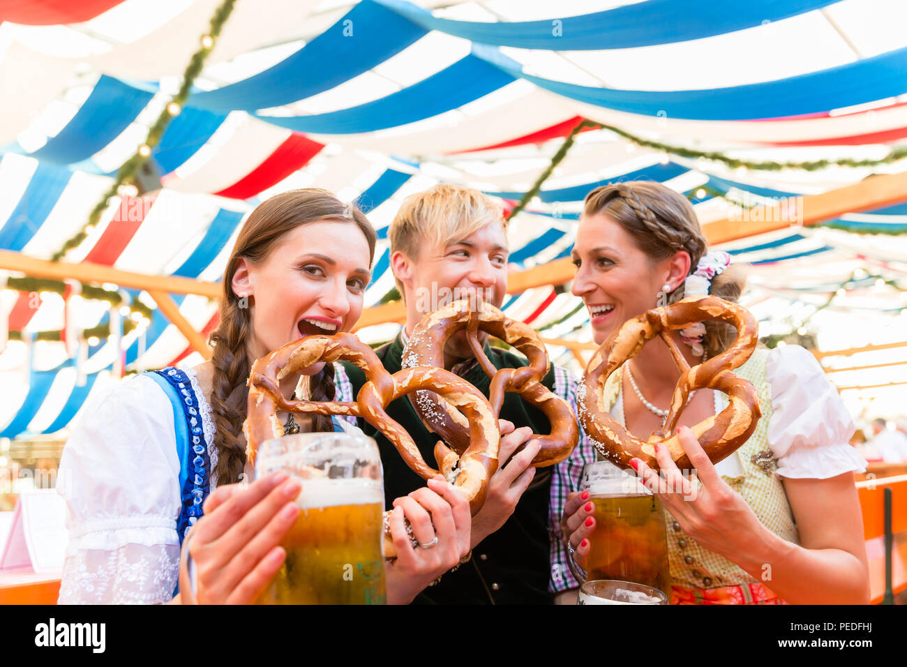 Freunde riesen Brezeln Essen und Trinken im Bierzelt Stockfoto