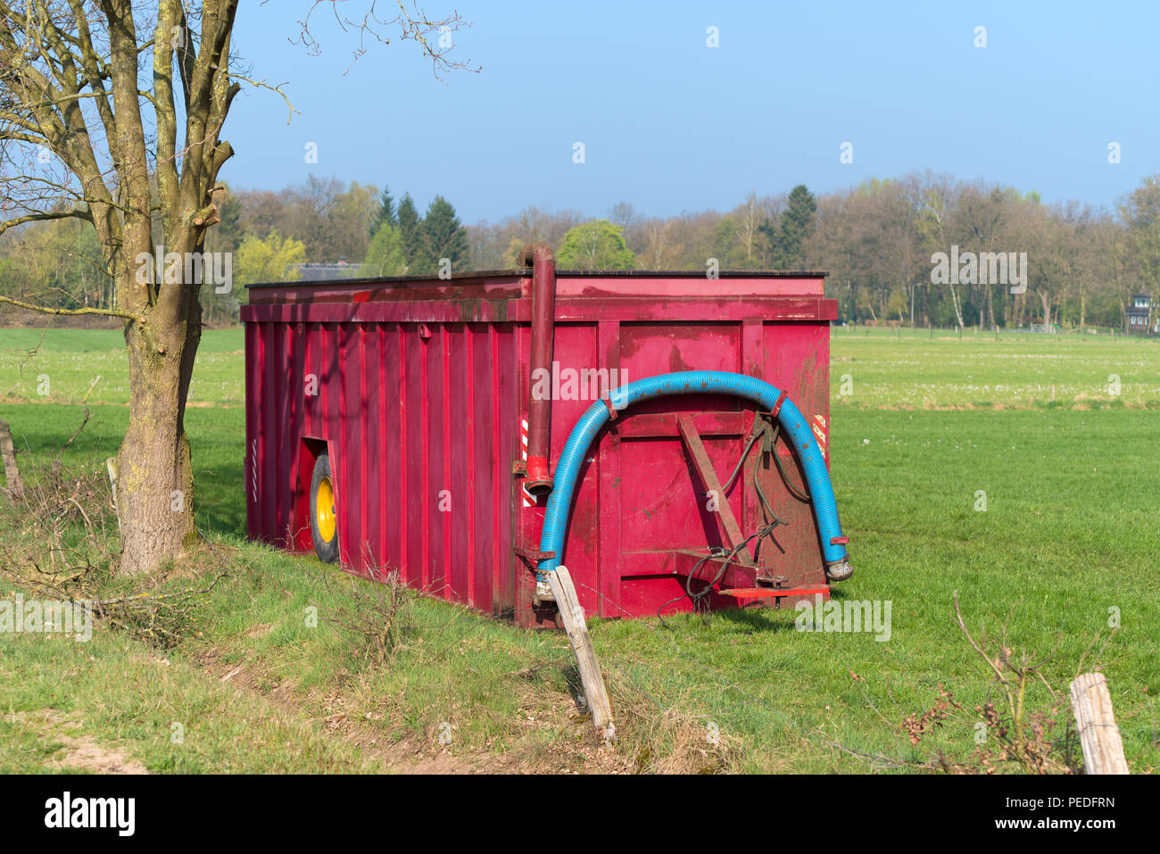 Große rote mobile Gülle Tank in einer Agrarlandschaft Stockfoto