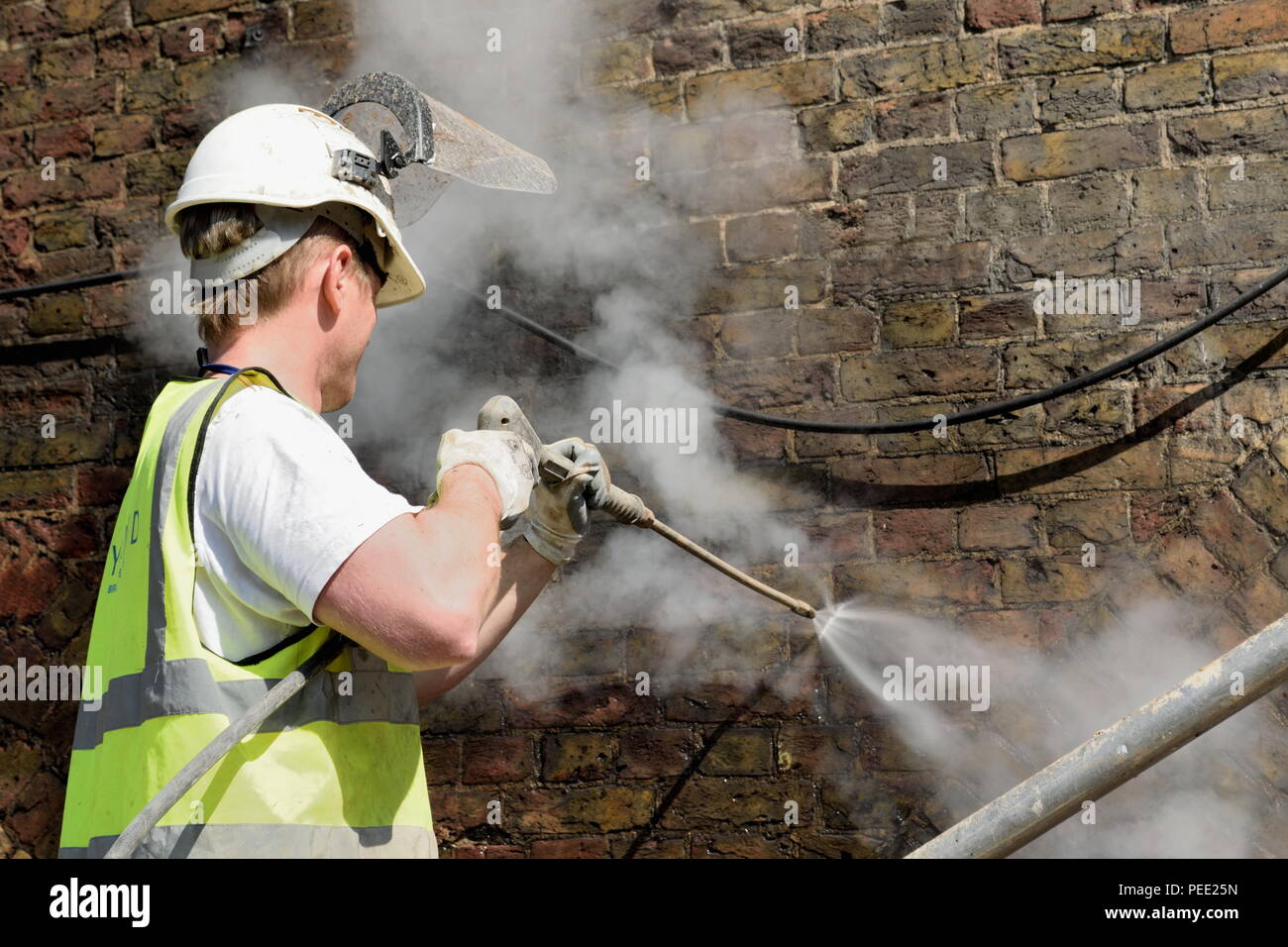 Arbeitnehmer Reinigung Wand mit hohem Druck Wasser sprühen Stockfoto