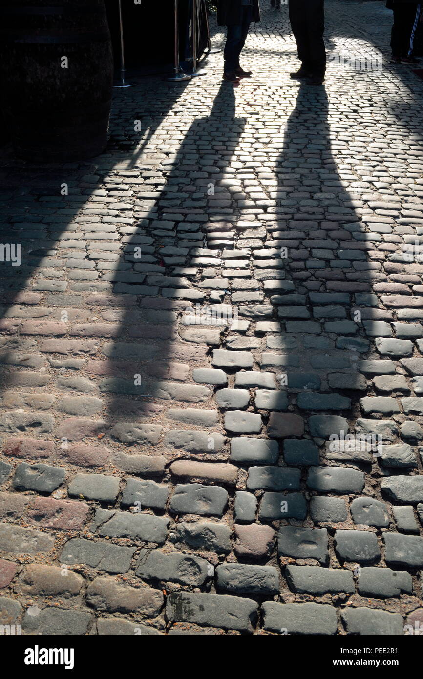 Die Schatten von Menschen in Gespräch auf einer Straße mit Kopfsteinpflaster in Camden Town, London Stockfoto