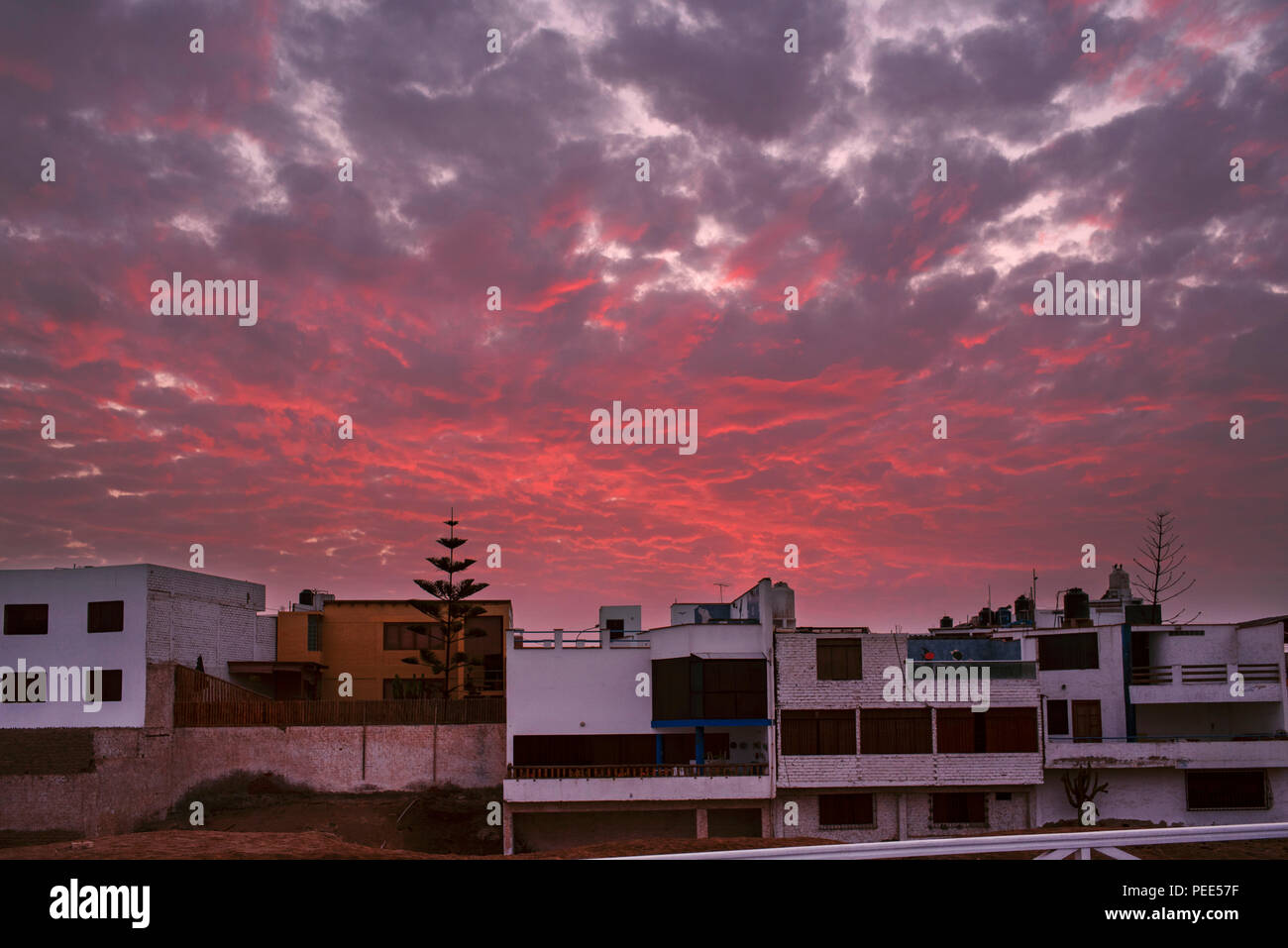 Dramatischer Sonnenuntergang über den weißen Häusern von Punta Hermosa (Surferdorf). Lima, Peru, Südamerika. Juli 2018 Stockfoto