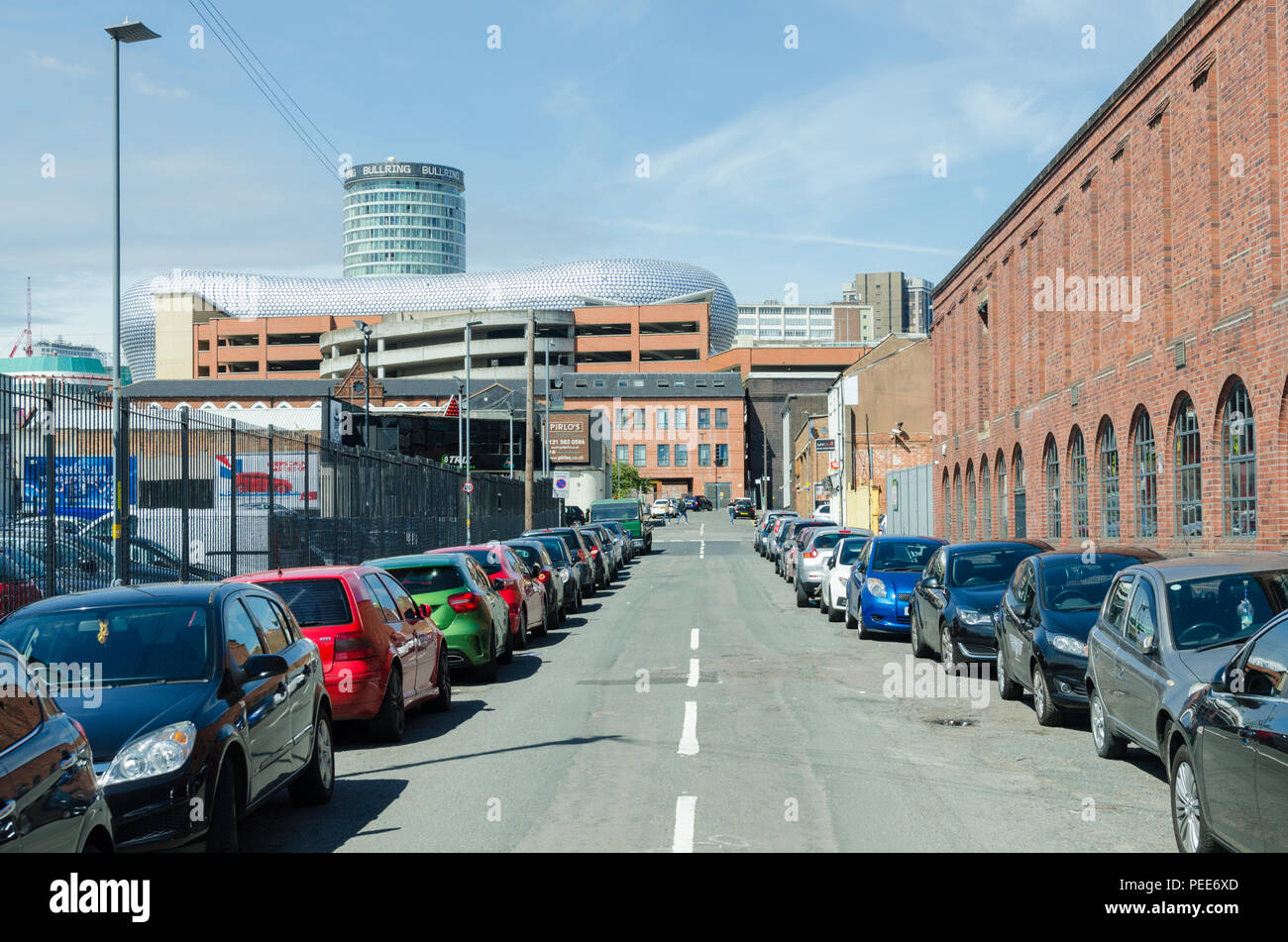 Lange Linie der geparkten Autos in Digbeth, Birmingham, in Richtung Stadtzentrum und Selfridges Gebäude und die Rotunde Stockfoto