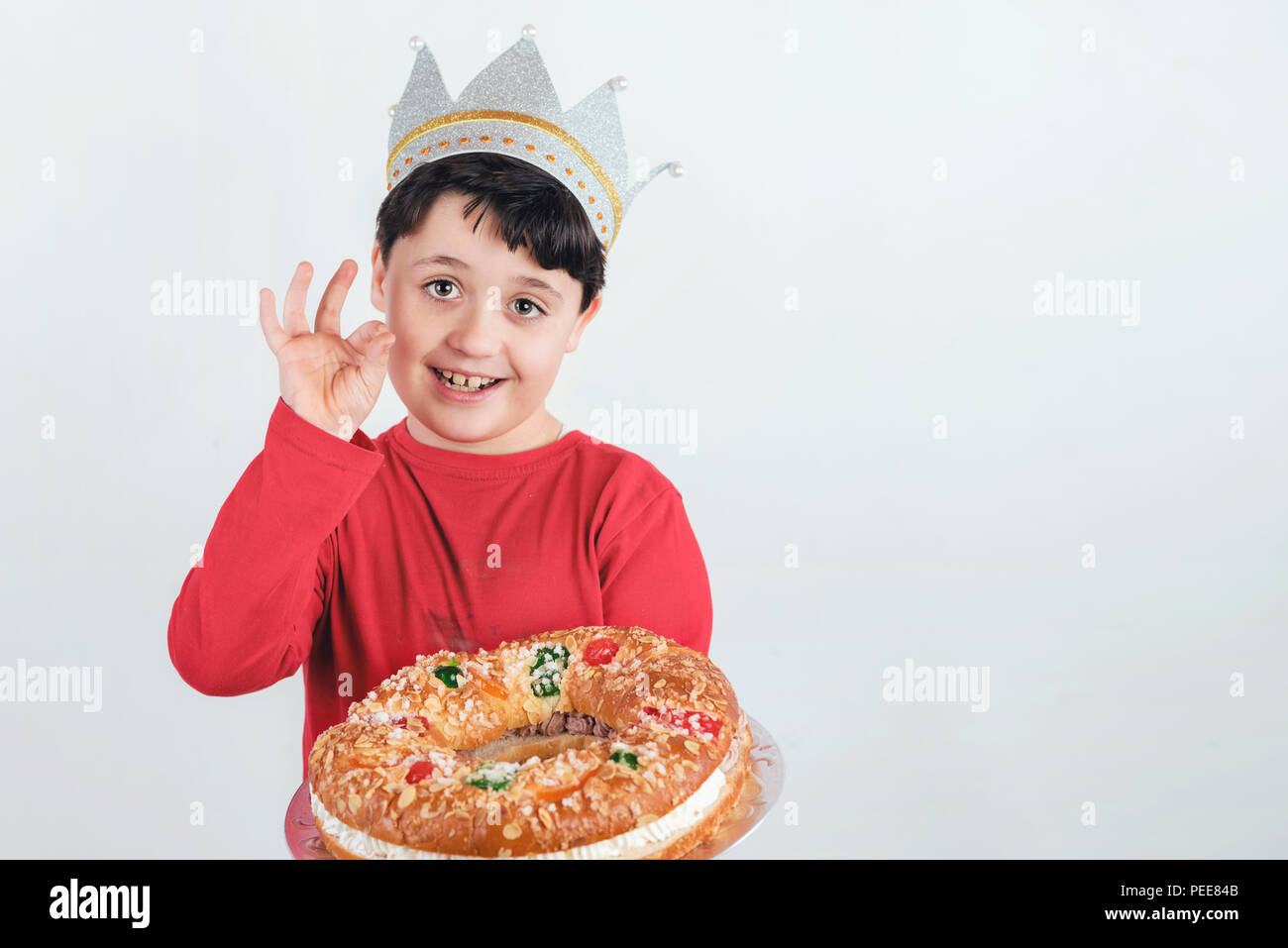 Lächelnd Kind mit König Kuchen oder Roscon de Reyes typisch spanisches Dessert für Weihnachten Stockfoto