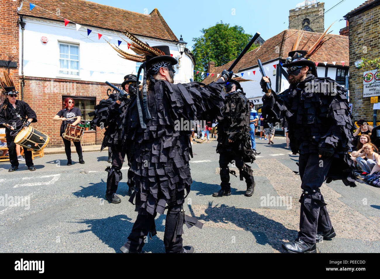 Traditionelle englische Volkstänzer, Wolfs Kopf Morris Dance Seite, in Schwarz tatter Jacken, Tanzen in der Straße am Sandwich Folk und Ale-Festival. Stockfoto