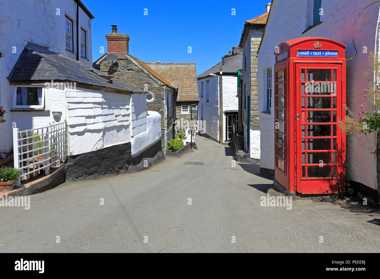 Weiß getünchten Häuschen und ein rotes Telefon Kiosk auf einer schmalen Straße in Port Isaac, Lage der ITV-Serie Doc Martin, Cornwall, England, Großbritannien. Stockfoto