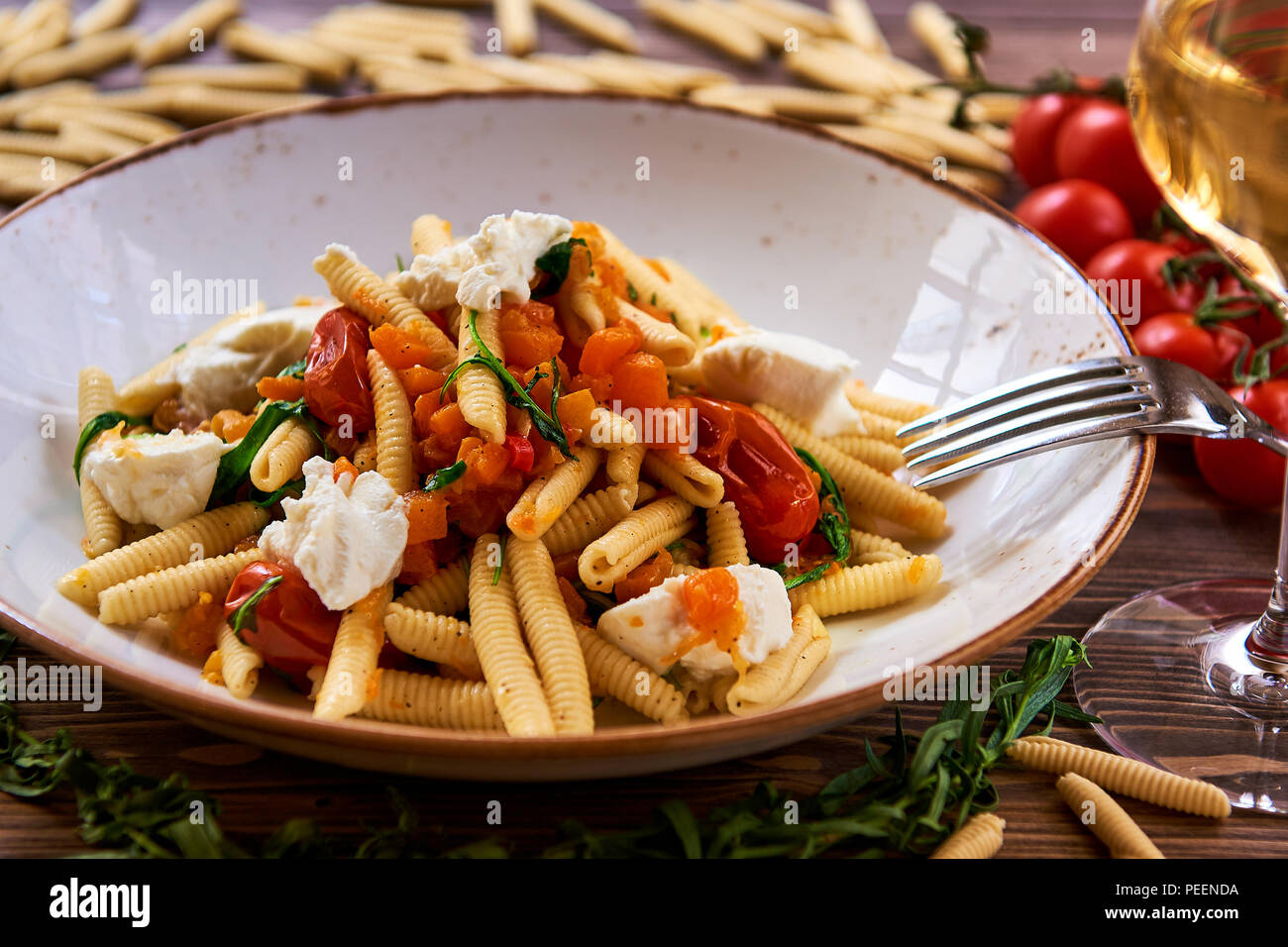 Vegetarische pasta garniert mit Tomaten, Käse und frischen Kräutern Stockfoto