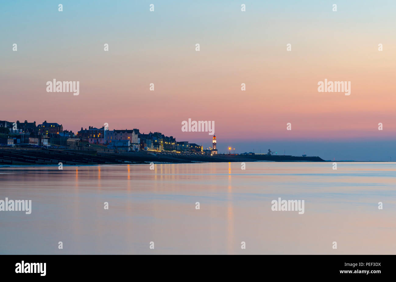 Herne Bay Seafront und Uhrturm mit einem bunten Dämmerung Himmel im Hintergrund beleuchtet. Stockfoto