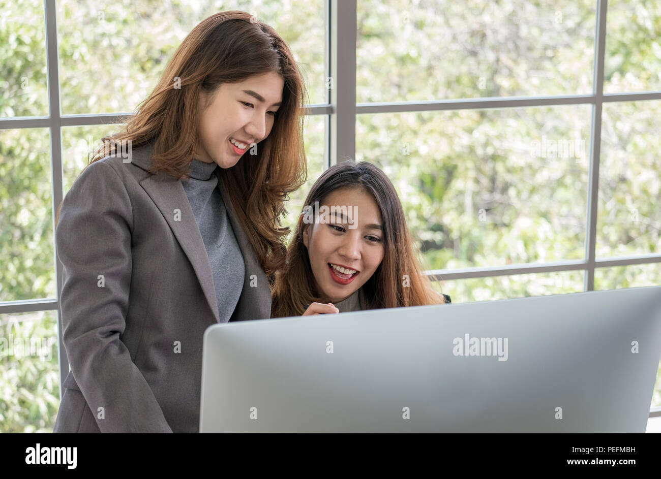 Zwei Kollegen Geschäftsfrau Diskussion über Arbeit verwenden Desktop Computer im Fenster in modernen Büro. Digital Business Lifestyle Konzept Stockfoto