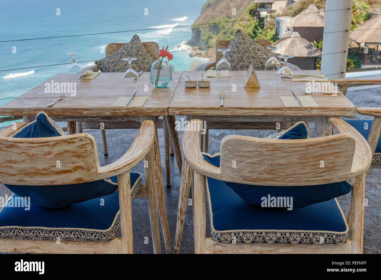 Holztisch und Stühlen an einem Outdoor Klippe Cafe mit Blick auf den Ozean, Tuban, Bali, Indonesien. Stockfoto