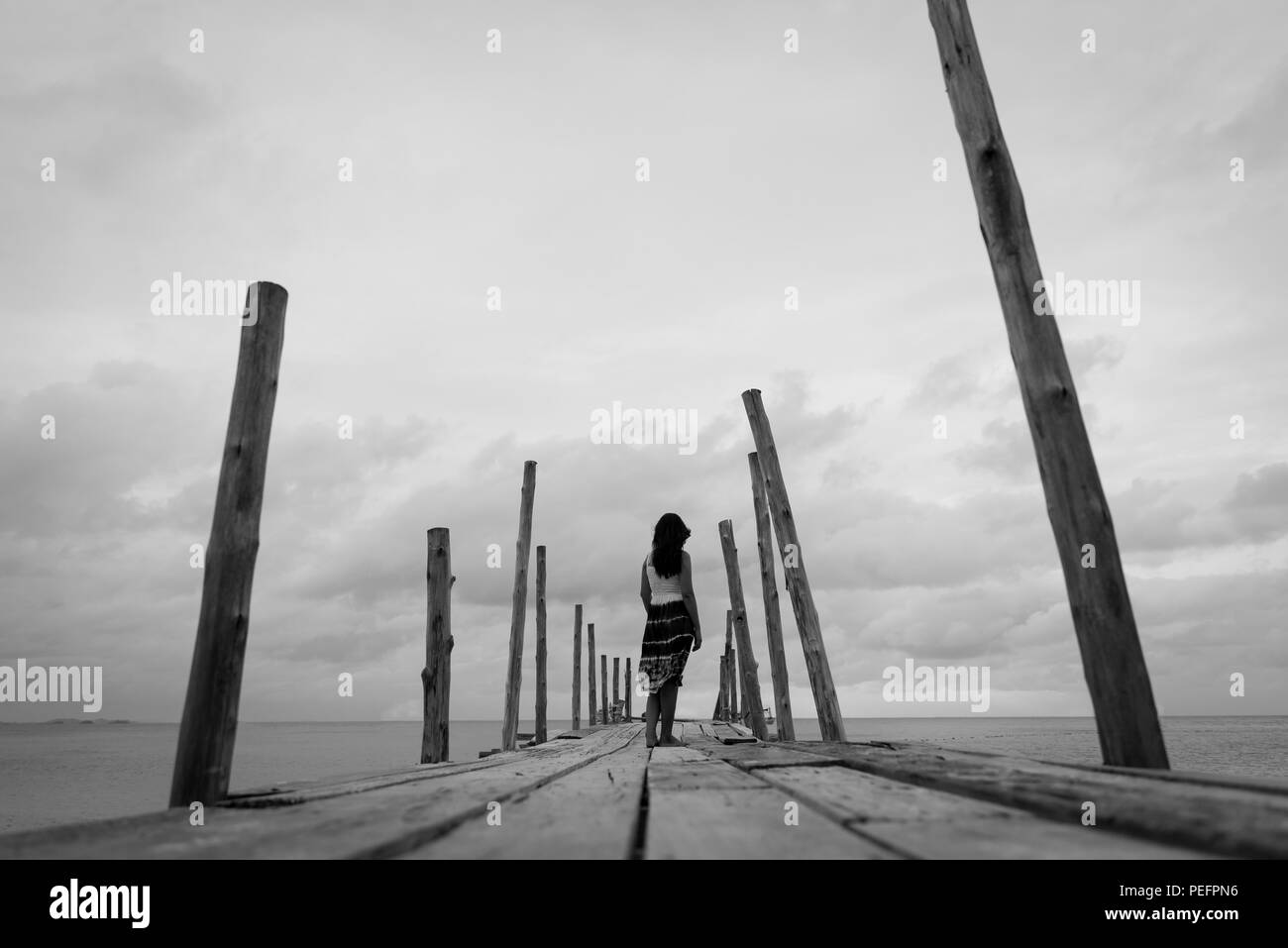 Schwarz Und Weiss Traurig Und Einsam Frau Allein Auf Einem Der Holzernen Brucke Uber Das Meer Stockfotografie Alamy