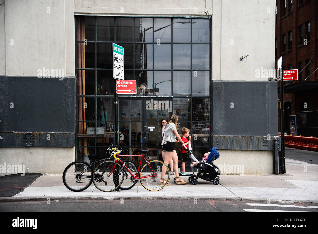 New York City, USA - Juni 20, 2018: die Menschen zu Fuß auf der Straße in Dumbo, Brooklyn, vor STOREFRONT von Restaurant mit Fahrräder geparkt. Stockfoto