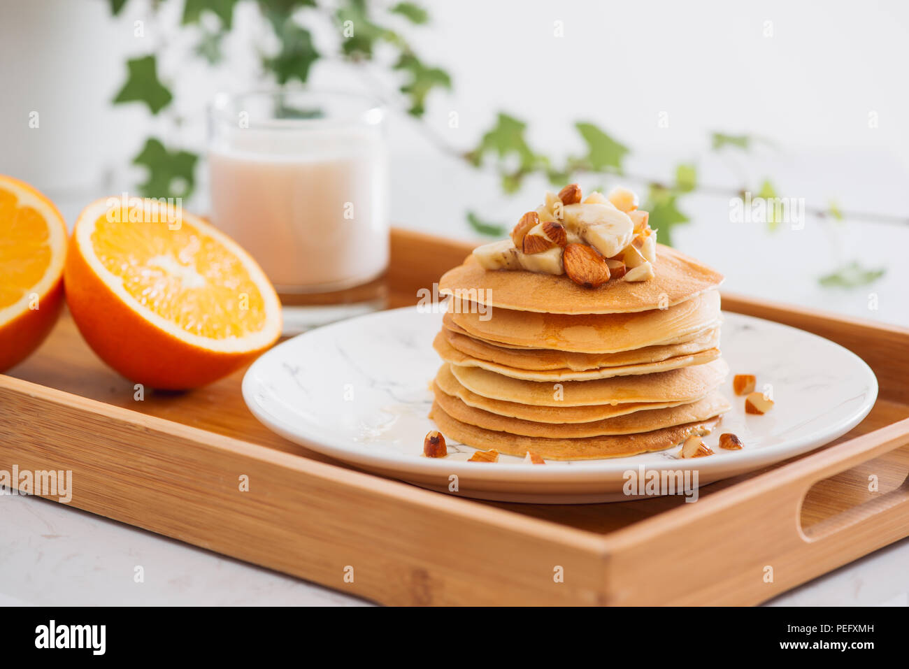 Stapel von leckeren Pfannkuchen mit Schokolade, Honig, Nüsse und Bananenscheiben auf Platte auf Stein Hintergrund Stockfoto