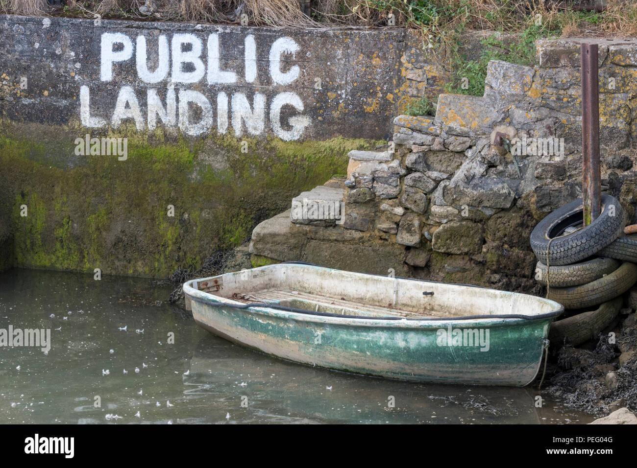 Einen kleinen schäbigen Ruderboot oder Beiboot günstig neben einem öffentlichen Landung Schritte bei Ebbe. Stockfoto