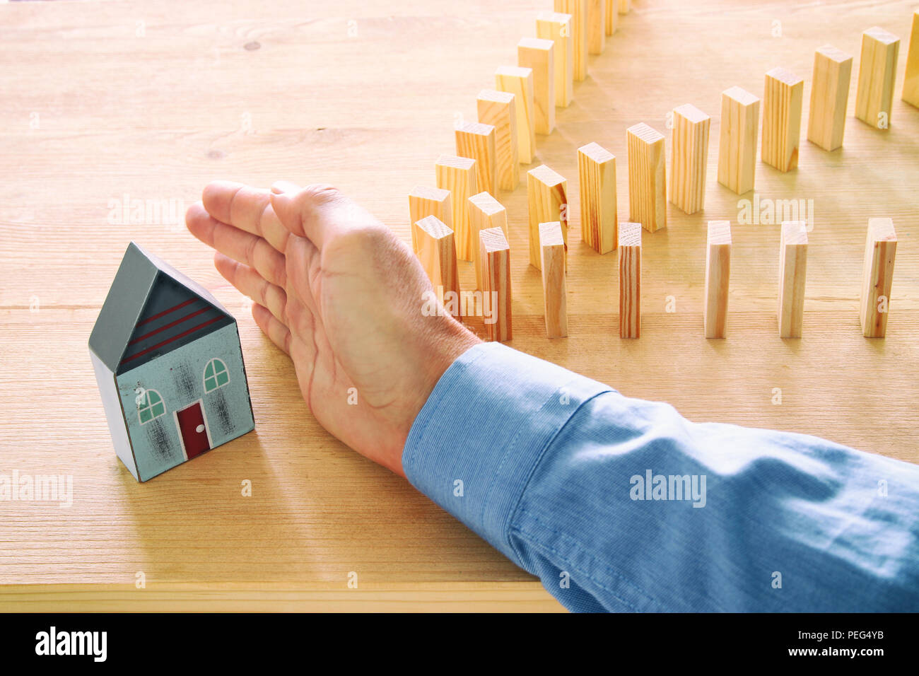 Konzept Bild von Immobilien Versicherungen und Schutz. Mann die Hände die Blockierung der Domino Effekt zu speichern, ein kleines Haus Stockfoto