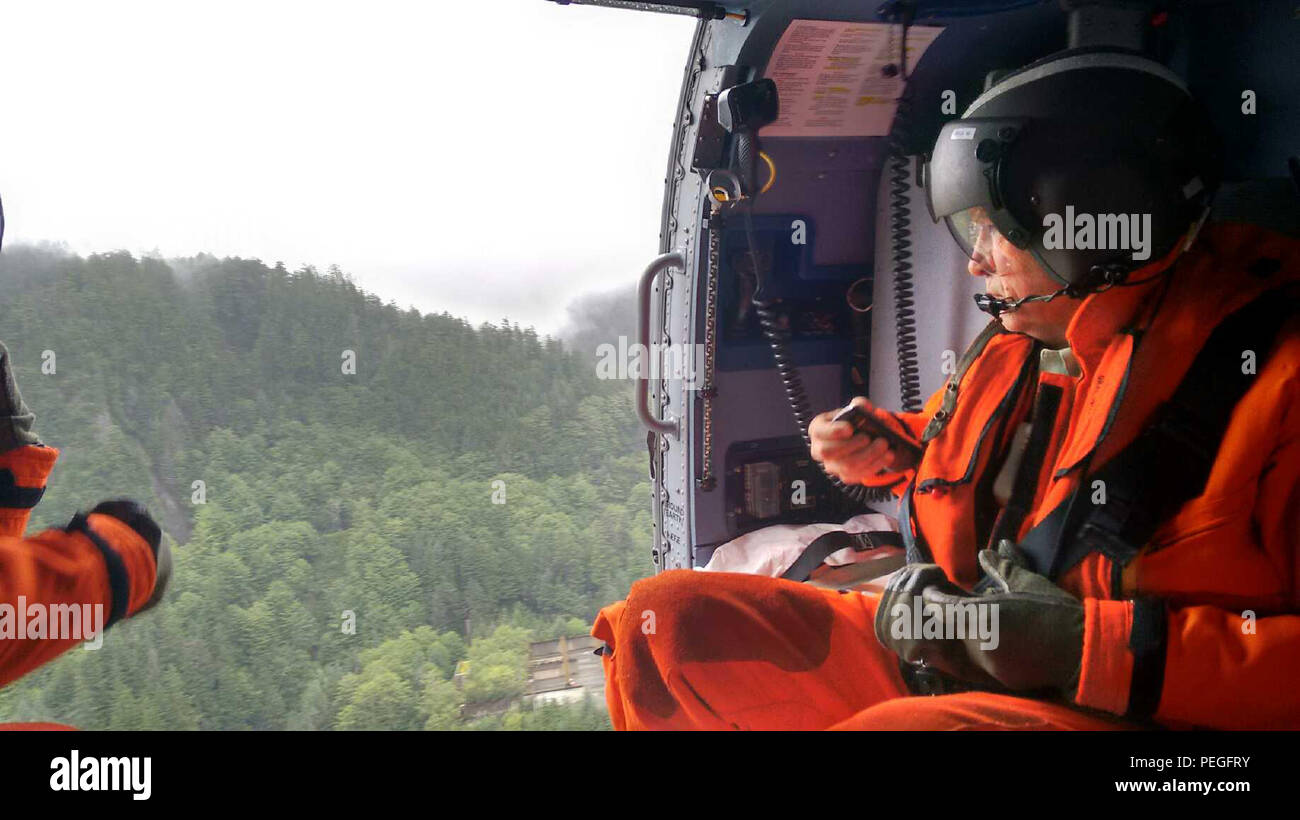 Alaska reg. Bill Walker bewertet das Ausmaß der Schäden, die durch Erdrutsche in Sitka, Alaska, bei einem Überflug an Bord eines Coast Guard Air Station Sitka MH-60 Jayhawk Helikopter August 19, 2015. Air Station Sitka Personal unterstützt mit Bewertung und Wiederherstellungsmaßnahmen und flog National Forest Service Boden und Wasser Experten, Sitka Bergrettung Personal- und Mandatsträger in den Erdrutsch Websites. (U.S. Coast Guard Foto) Stockfoto