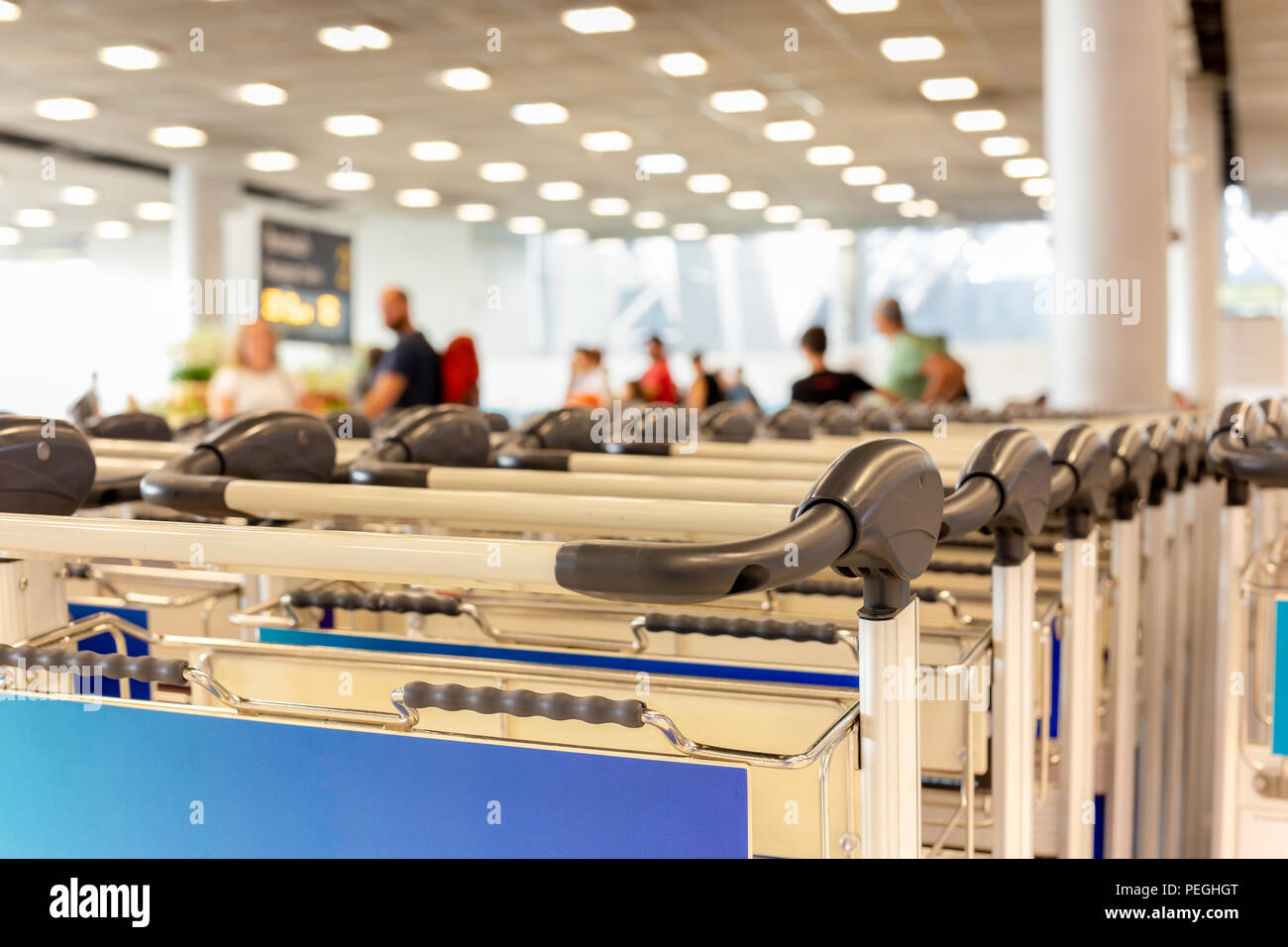 Reihe von Gepäckwagen in der Flughafen mit dem Pkw im Hintergrund. Stockfoto