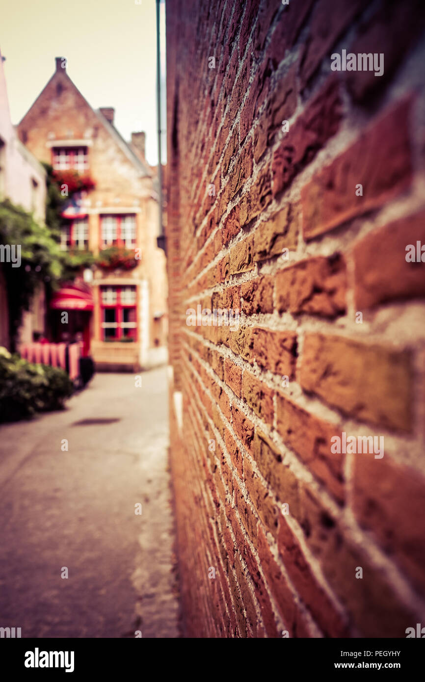 Porträt Blick auf einer der Straßen von Brügge in Belgien, mit einem verschwommenen Mauer im Vordergrund und ein kleines Restaurant in der Rückseite Stockfoto