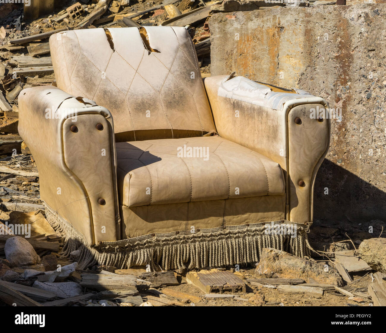 Vintage beige Leder Lounge Chair (arm oder Club Chair) mit großen Bolzen und einer Quaste Fringe. Gefunden aufgegeben und beschädigt. Stockfoto