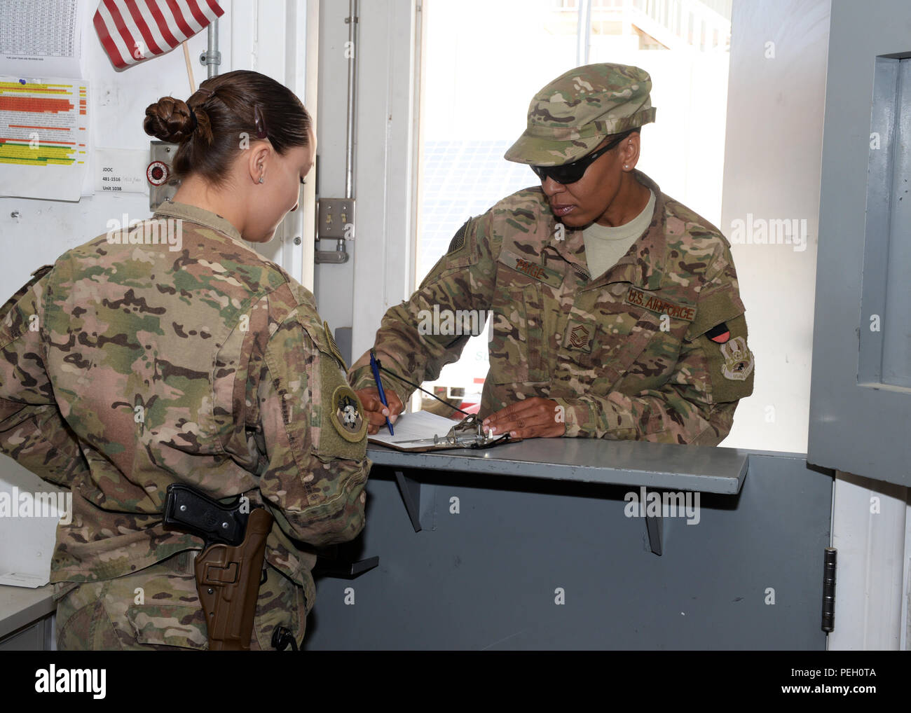 Us Air Force Staff Sgt. Brenda Hawkins, 455Th Expeditionary Logistik Bereitschaft Squadron Unteroffizier in der Armory, gibt Papierkram Senior Master Sgt. Vinetta Paige, 455 ELRS Material Management Flug Chief, vor ist die Ausstellung von ihr eine Waffe 26.08.2015, in Bagram Air Field, Afghanistan. Die Armory Team ist zuständig für die Ausstellung von Waffen zu Flieger der 455th AEW, die mit nicht bereitstellen, erfordern aber eine Waffe während der Bereitstellung. (U.S. Air Force Foto von älteren Flieger Cierra Presentado/Freigegeben) Stockfoto