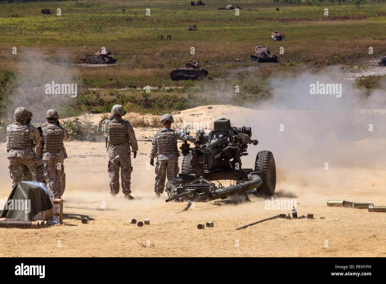 Soldaten, die in den Th 3-112 Field Artillery, New Jersey Army National Guard, zusehen, wie 2. Lt. Jennifer Wain die digitale M119A3 105mm leichte Haubitze während einer Live Fire Übung in Joint Base Mc Guire-Dix - Lakehurst, New Jersey, 12.08.26, 2015 Feuer. Wain, ein Feuer Richtung Offizier mit der 3-112., ist die erste weibliche Combat Arms Officer in der Geschichte der New Jersey Army National Guard. Der M 119 A3 mit einem digitalen Brand Control System mit einem inertialen Navigationssystem ausgerüstet ist, geführte - Precision System Technologie und andere Funktionen, die die Waffe die Fähigkeit, det geben Stockfoto