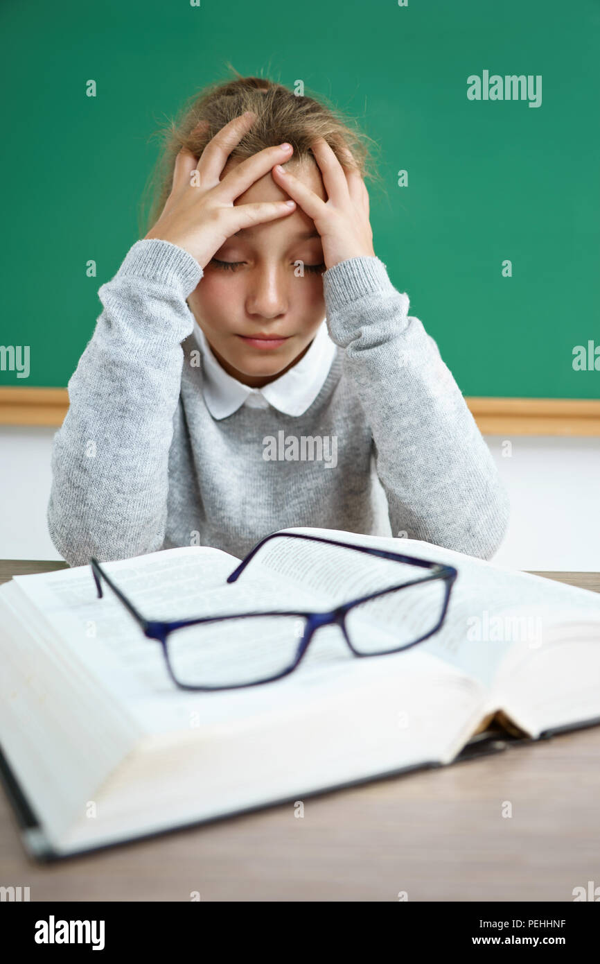 Mädchen ihren Kopf umgekippt. Foto von Schulmädchen mit Buch auf dem Schreibtisch im Klassenzimmer. Zurück zur Schule Stockfoto