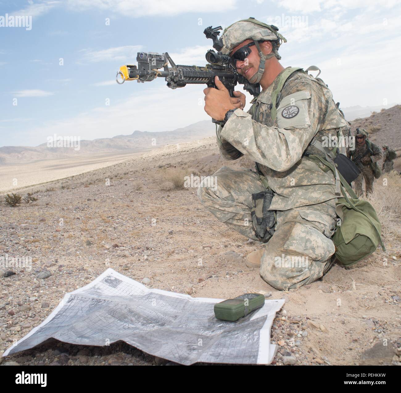 Fire team leader Sgt. Dustin Schwarz nutzt seine vergrößerte Waffe Anblick erleichtert eine Anfrage für Indirektes Feuer auf einen Feind Position an der National Training Center (NTC) in Fort Irwin, Calif., Aug 25., 2015. Heute war der vierte und letzte Tag einer Brigade - Größe Kraft - Kraft simulierten Gefecht zwischen den 116 CBCT- und gegensätzlichen Kräfte (AUFSTÄNDISCHE) von der 2. Staffel, 11. ACR. (U.S. Nationalgarde Foto von Maj. W. Chris Clyne, 115 Mobile Public Affairs Ablösung/Freigegeben) Stockfoto