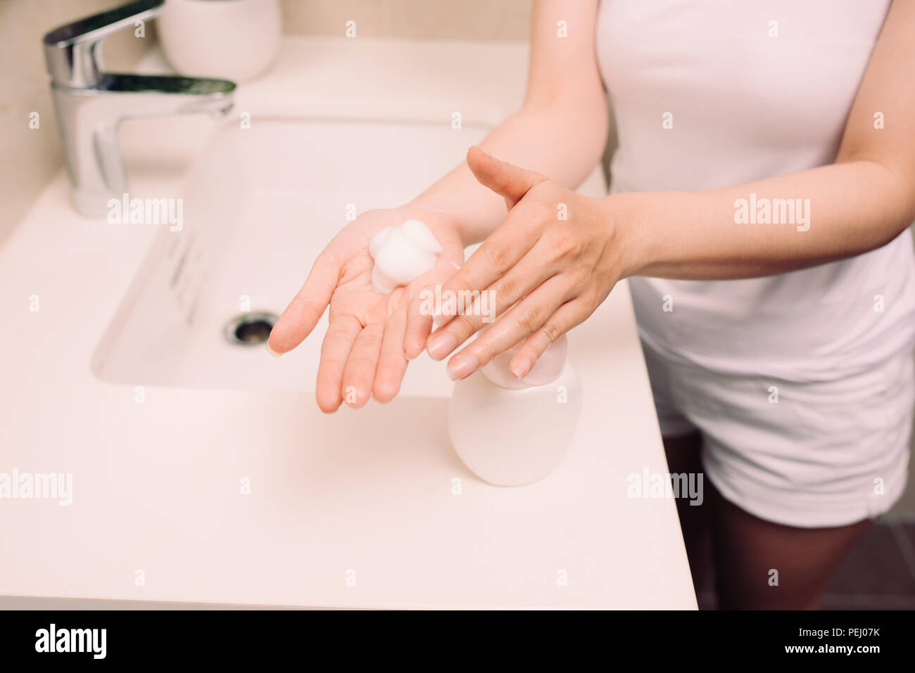 Frau waschen Sie Ihr Gesicht mit Foam Cleanser am Morgen Stockfoto
