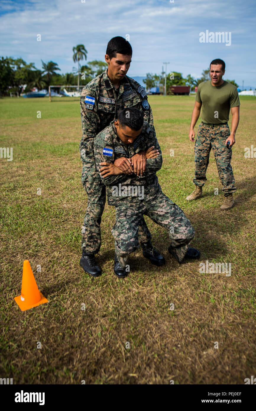 Us Marine Corps Cpl. Diego Rendon, rechts, der Teamleiter für die Zusammenarbeit in Sicherheitsfragen Team-Honduras, Special Purpose Marine Air-Ground Task Force-Southern Befehl fördert die honduranische Marine während des Manövers unter Feuer Teil der Bekämpfung der Fitness Test am Marinestützpunkt Puerto Castilla, Honduras, 12.08.2015. SCT-Honduras ist derzeit als Teil der SPMAGTF-SC bereitgestellt werden, um das Centro de Adiestramiento Naval mit der Umsetzung eines Lehrplans einen Honduranischen marine Programm zu schaffen, zu unterstützen. (U.S. Marine Corps Foto von Cpl. Katelyn Hunter/Freigegeben). Stockfoto