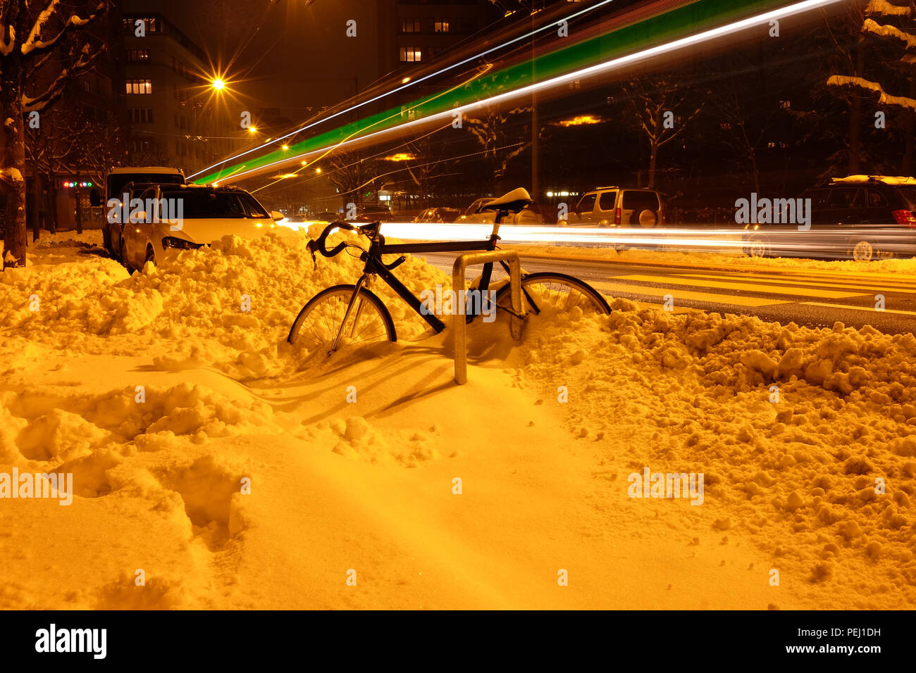 Lange Belichtung geschossen von den Straßen von Fribourg in der Schweiz, mit Schnee auf der Straße, ein Fahrrad und Fahrzeug Licht im Hintergrund Wanderwege Stockfoto