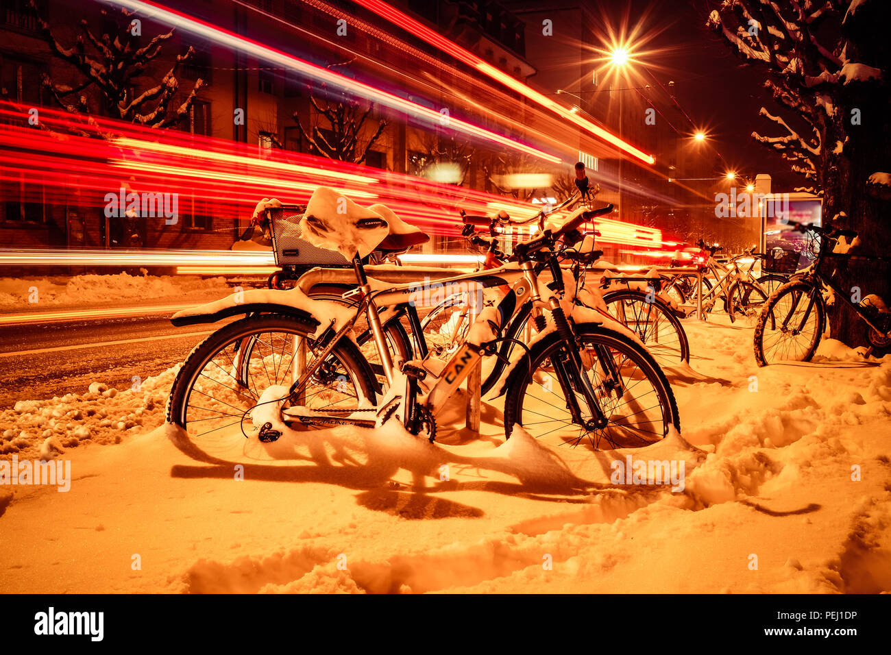 Lange Belichtung geschossen von den Straßen von Fribourg in der Schweiz, mit Schnee auf der Straße, Fahrräder und Fahrzeug leichte Wanderwege im Hintergrund Stockfoto