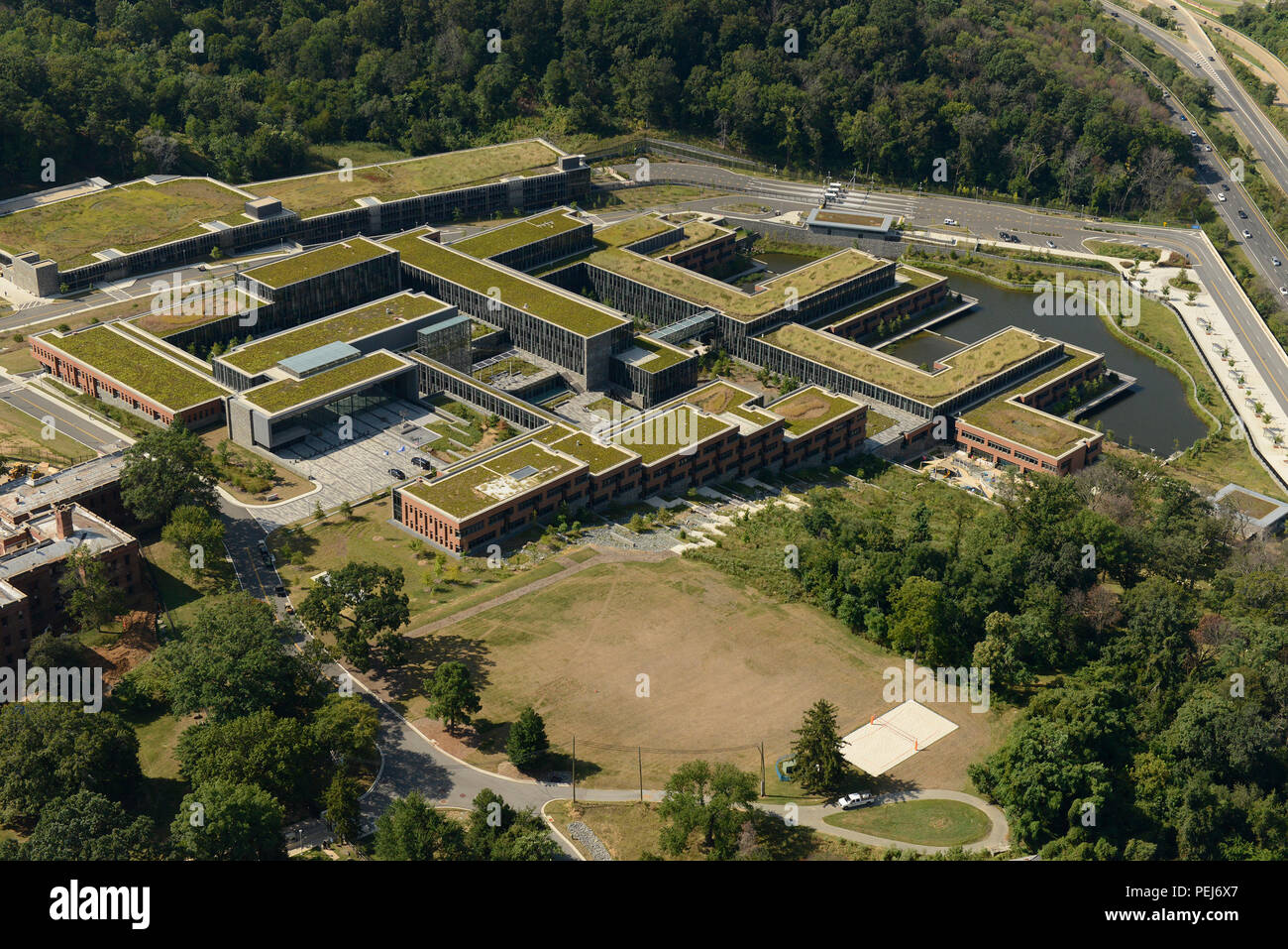 Das Douglas A. Munro Coast Guard Headquarters Building im Südosten von Washington, D.C., wird von einem MH-65 Dolphin Hubschrauber gezeigt. Das Gebäude wurde 2013 im Rahmen der Konsolidierung des Department of Homeland Security am St. Elizabeths West Campus fertiggestellt und unterstützt USCG-Operationen, Verwaltung, Personal und Sicherheit. LEED-zertifiziertes Design fördert Nachhaltigkeit und Energieeffizienz und bietet gleichzeitig moderne Büroeinrichtungen für die Führung der Küstenwache und verbessert die Einsatzbereitschaft und Koordination. Stockfoto