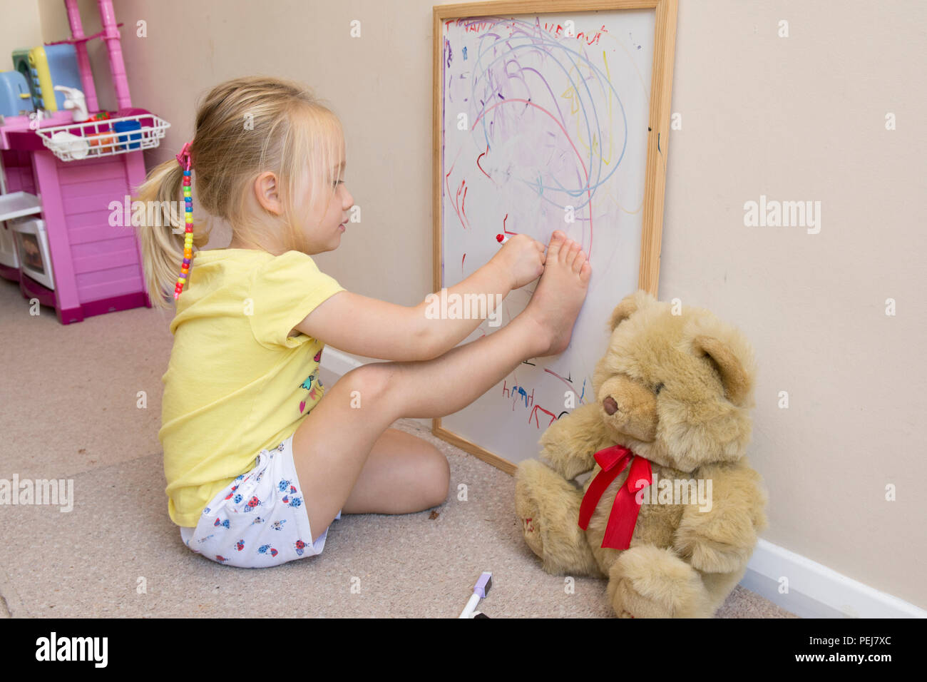 Junge zwei Jahre altes Mädchen Zeichnung mit Farbstift auf dem Whiteboard, künstlerische, Zeichnung um den Umriss des Fußes. Stockfoto