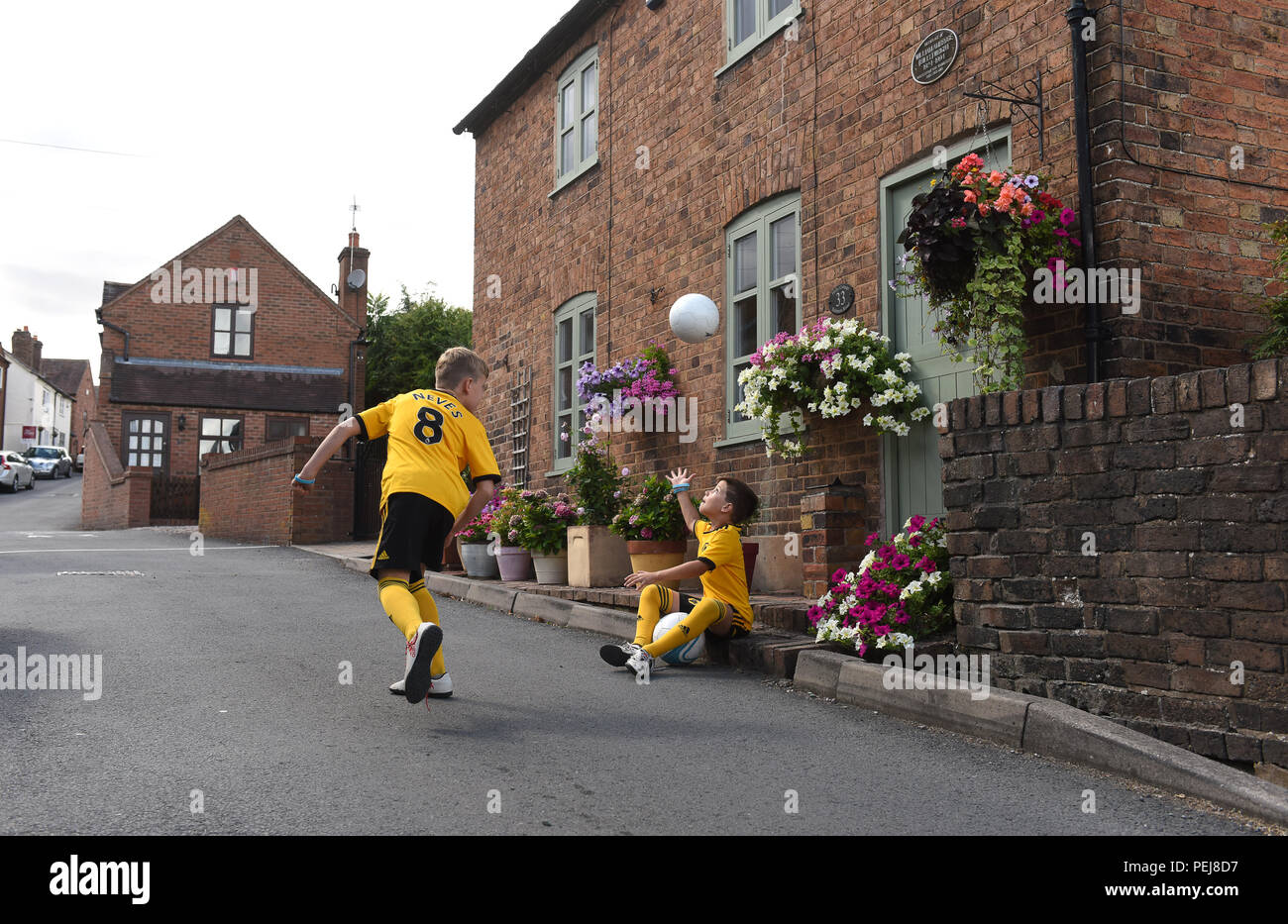 Jungen in Wolverhampton Wanderers FC Replik kits Fußball spielen außerhalb der Geburtsort von Wölfen und England Fußball-Legende Billy Wright in Ironb Stockfoto