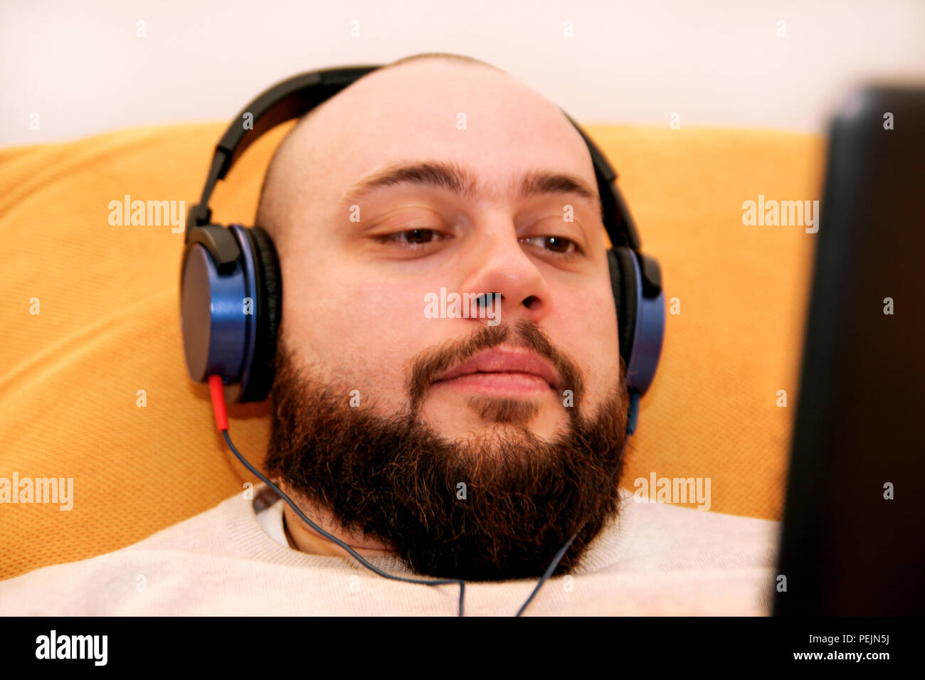 Cool guy Musikhören zu Hause auf dem Tablet-PC. Junger Mann mit Kopfhörer zu Hause entspannen, Musik hören und spielen video spiel mit Tablet. Stockfoto
