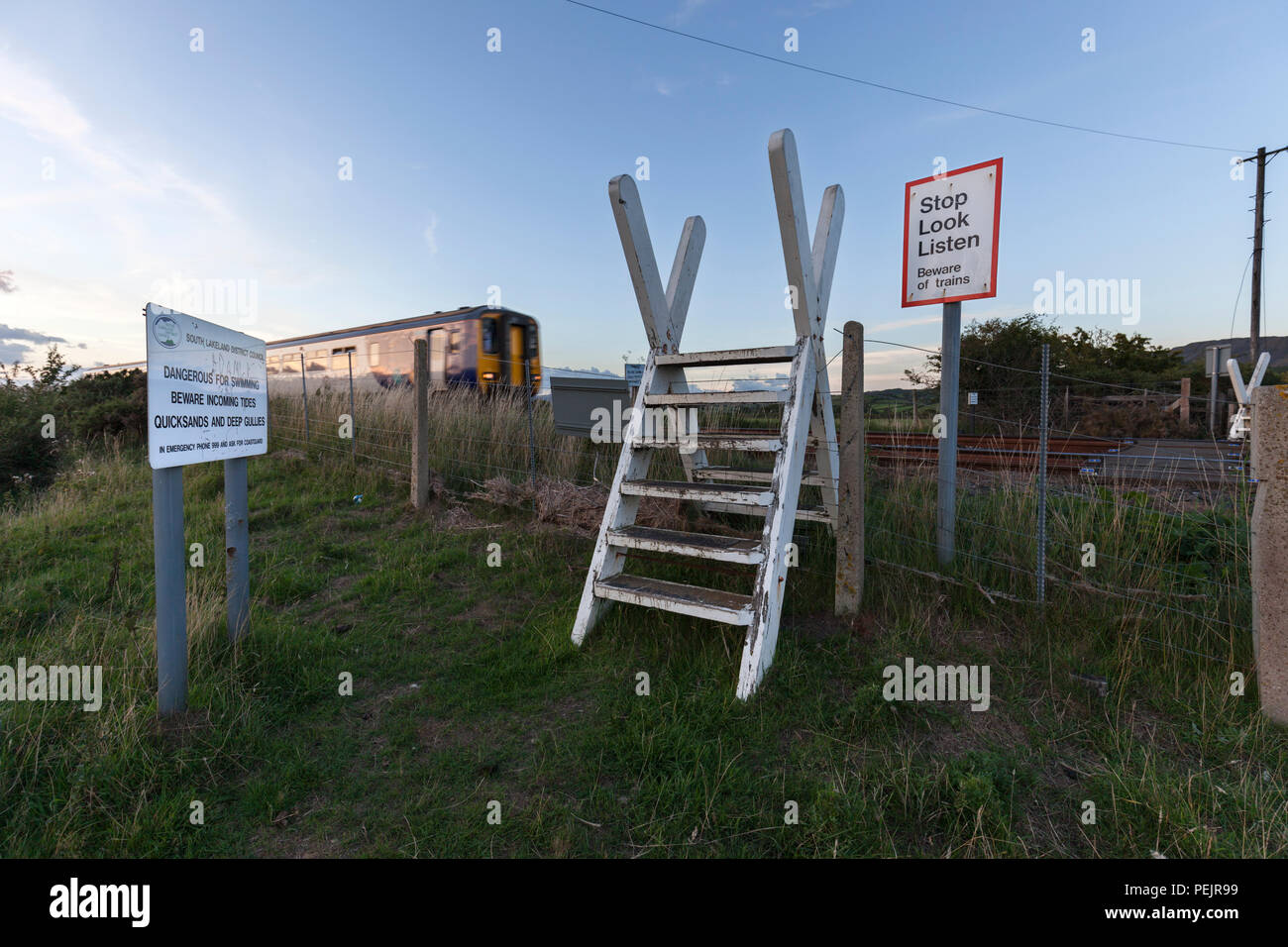 Eine nördliche Bahn Klasse 156 Sprinter Zug passiert den öffentlichen Fuß Überfahrt über die Bahnstrecke Kirkby In Furness mit Stop look Listen unterschreiben. Stockfoto